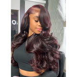 A voluminous dark burgundy body wave wig with transparent lace front and pre-plucked hairline side parting