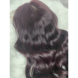 A deep burgundy body wave wig with a transparent lace front and pre-plucked hairline featuring a side parting