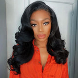 A woman wearing a vibrant orange shirt modeling a wavy lace upgraded hairline wig with 150% density